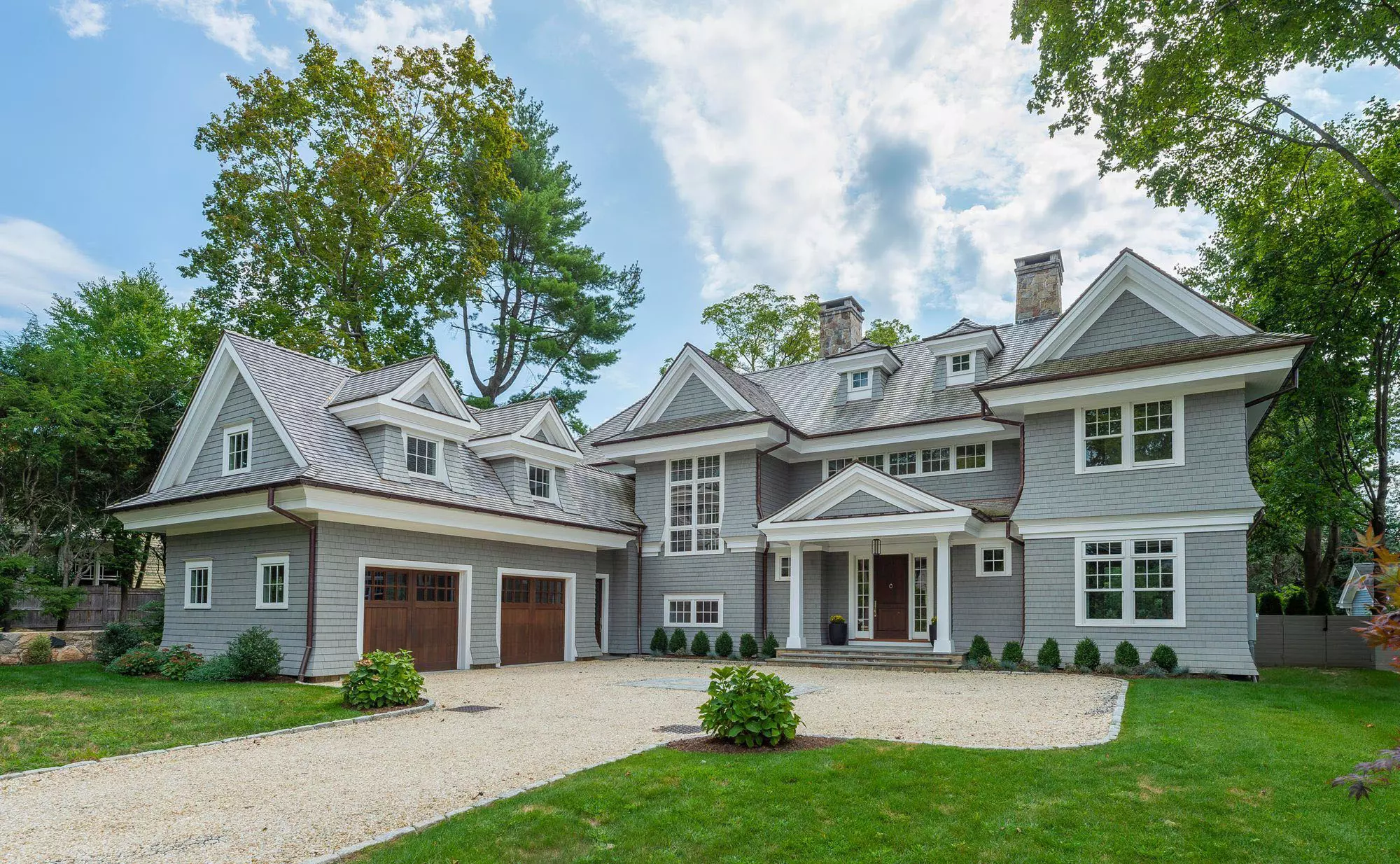 Stunning custom home with an A-frame portico above the front door supported by two square columns.