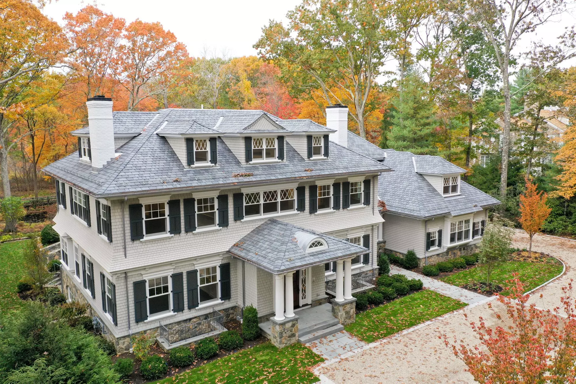 Beautiful custom home with a hip roof portico supported by 4 round columns & stone bases.