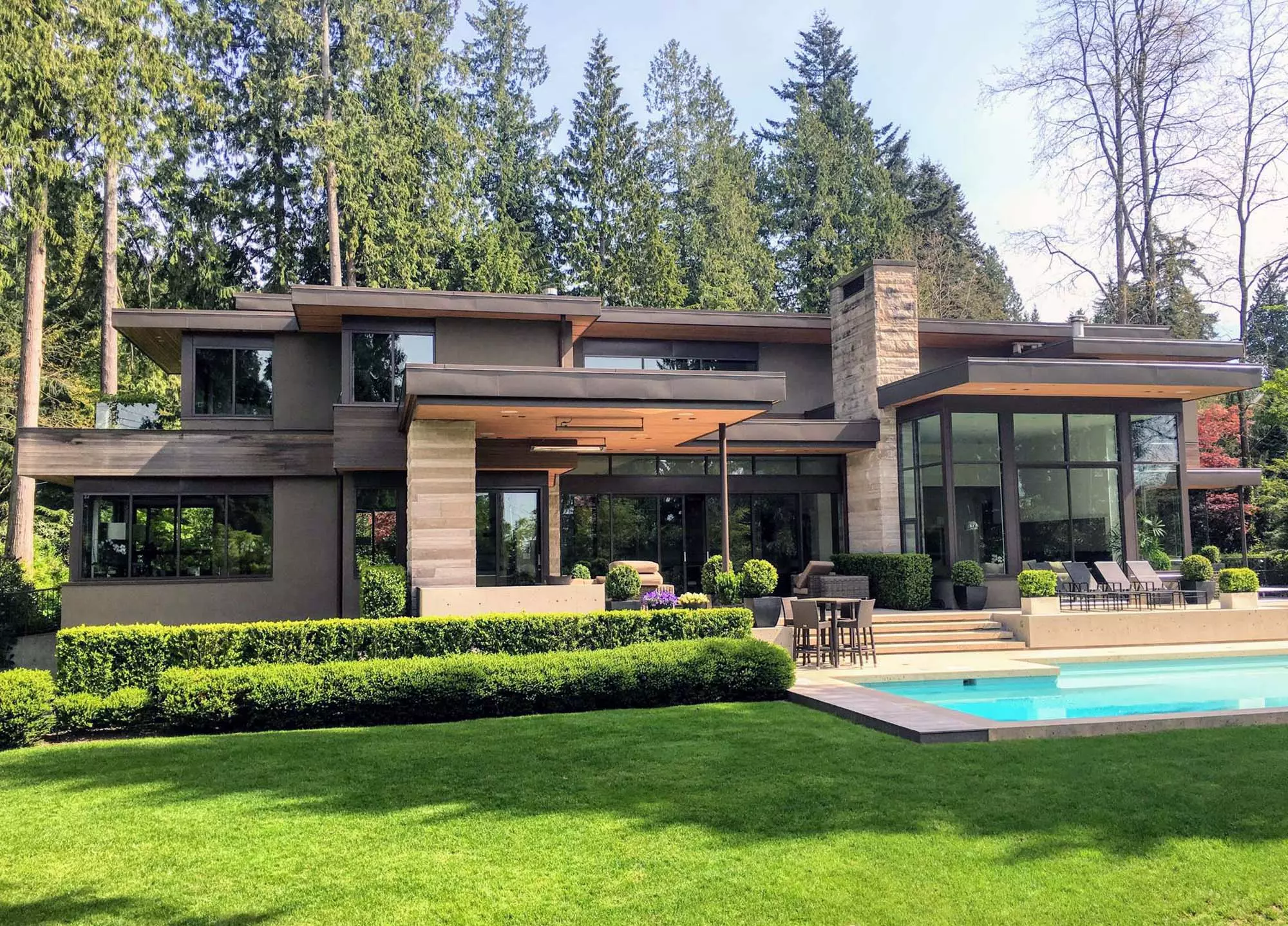 Beautiful modern style home with a flat roof portico trimmed with metal and wood.