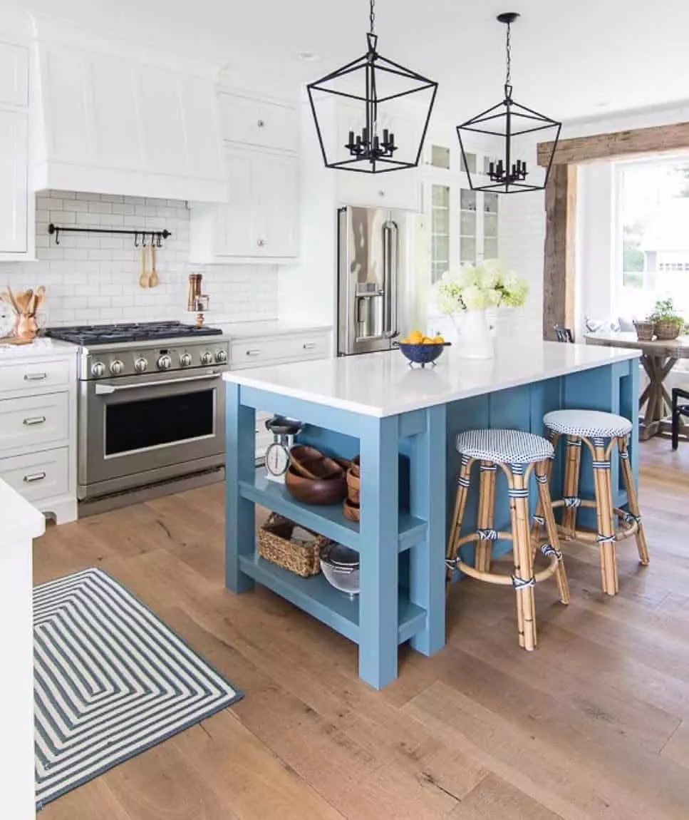 Brass lights with white countertops and blue kitchen island