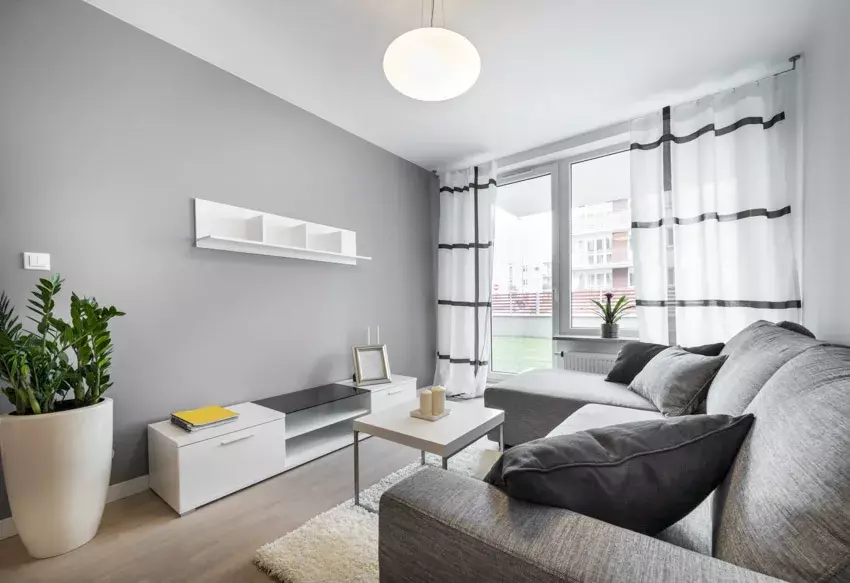 Living room with gray walls, pendant light, couch, and windows