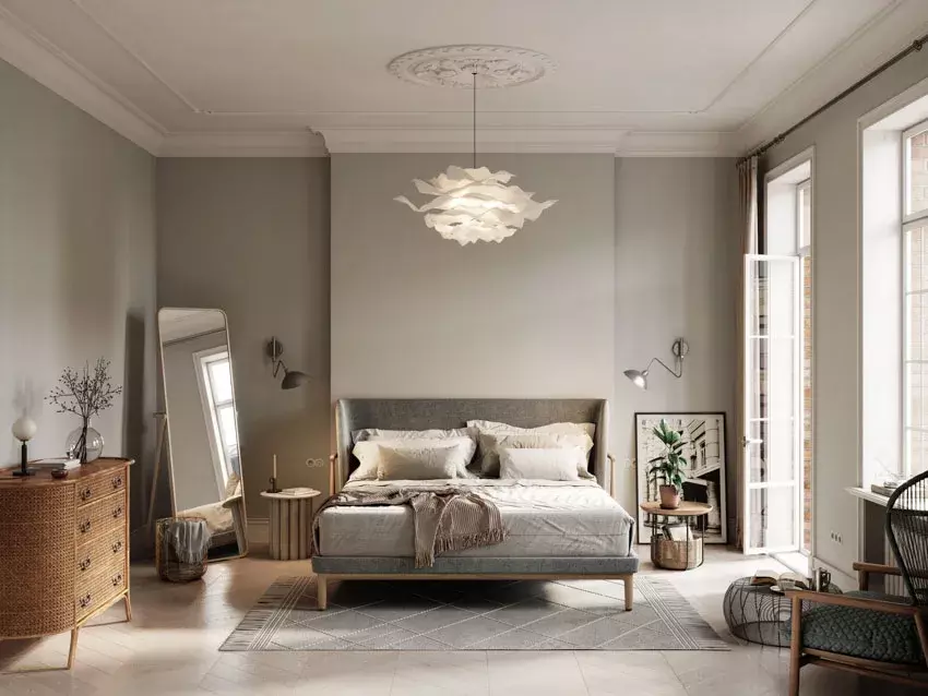 Bedroom with gray wall, tray ceiling, indoor plant, nightstand, lamp, and windows