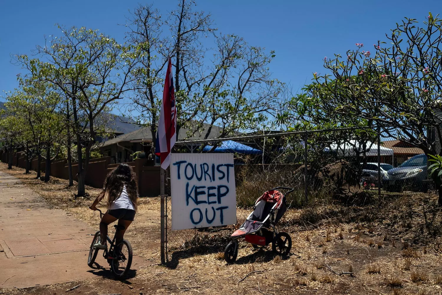 A girl rides her bike past a sign that says "Tourist Keep Out," in Lahaina, Hawaii, Thursday, Aug. 17, 2023. Long before a wildfire blasted through the island of Maui the week before, there was tension between Hawaii