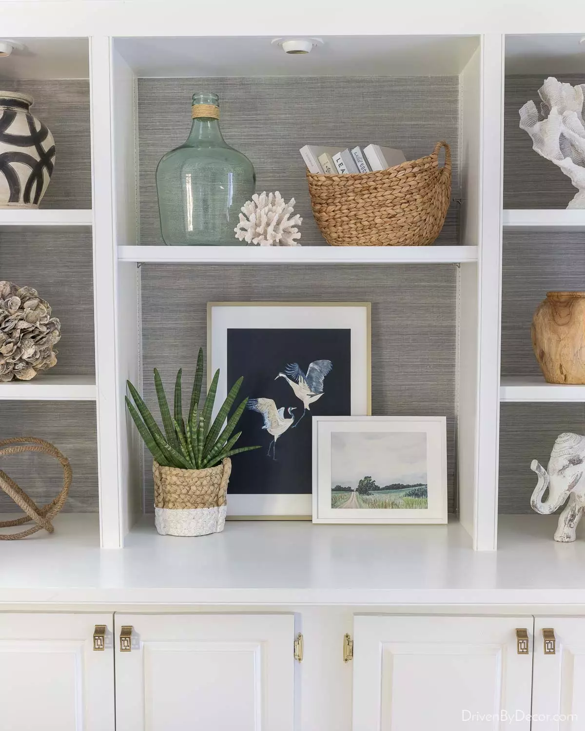 Charcoal grasscloth wallpaper makes the decor pieces on this bookcase pop!