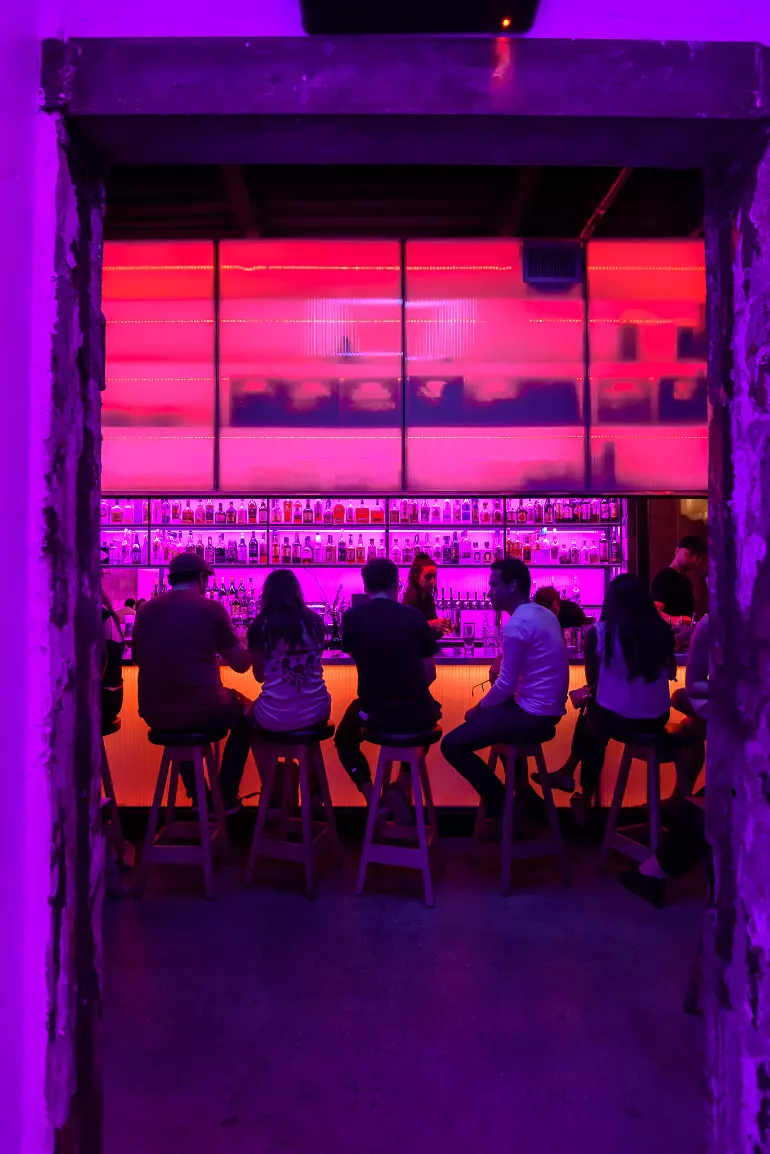 Pink and purple hues bathe this bar in moody light.