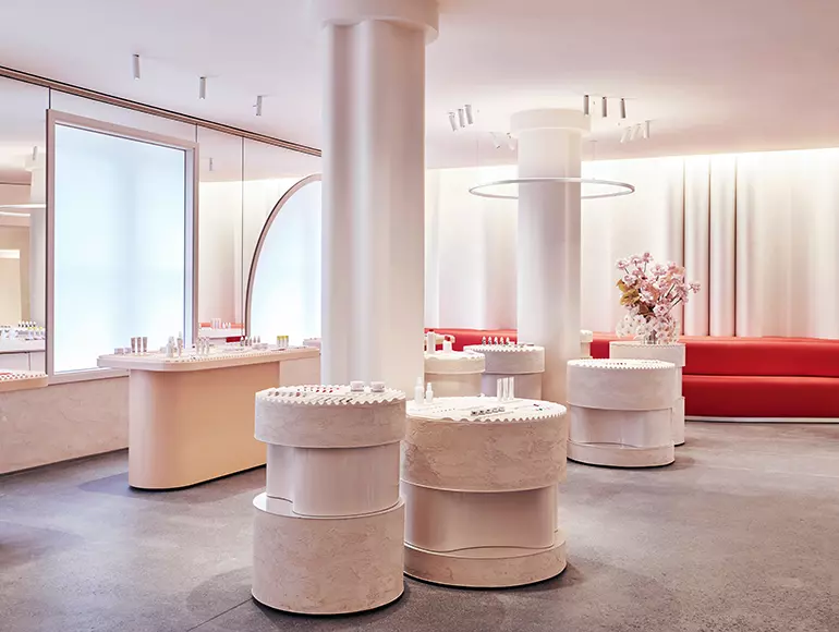 Glossier showroom with pale pink walls and circular makeup displays