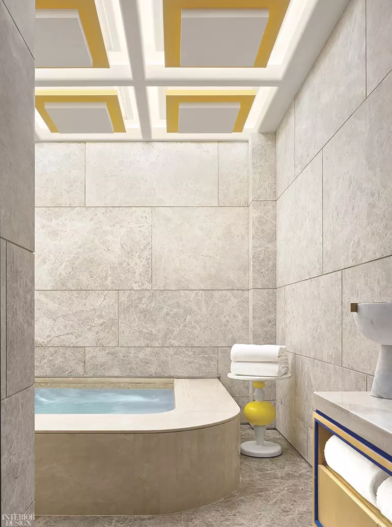 This modern bath features a curved tub with cement walls and golden accents