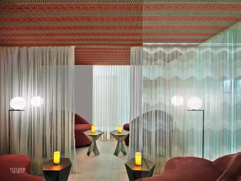 Wooden slats line this massage room, with a white massage bed at the center and flowing candles