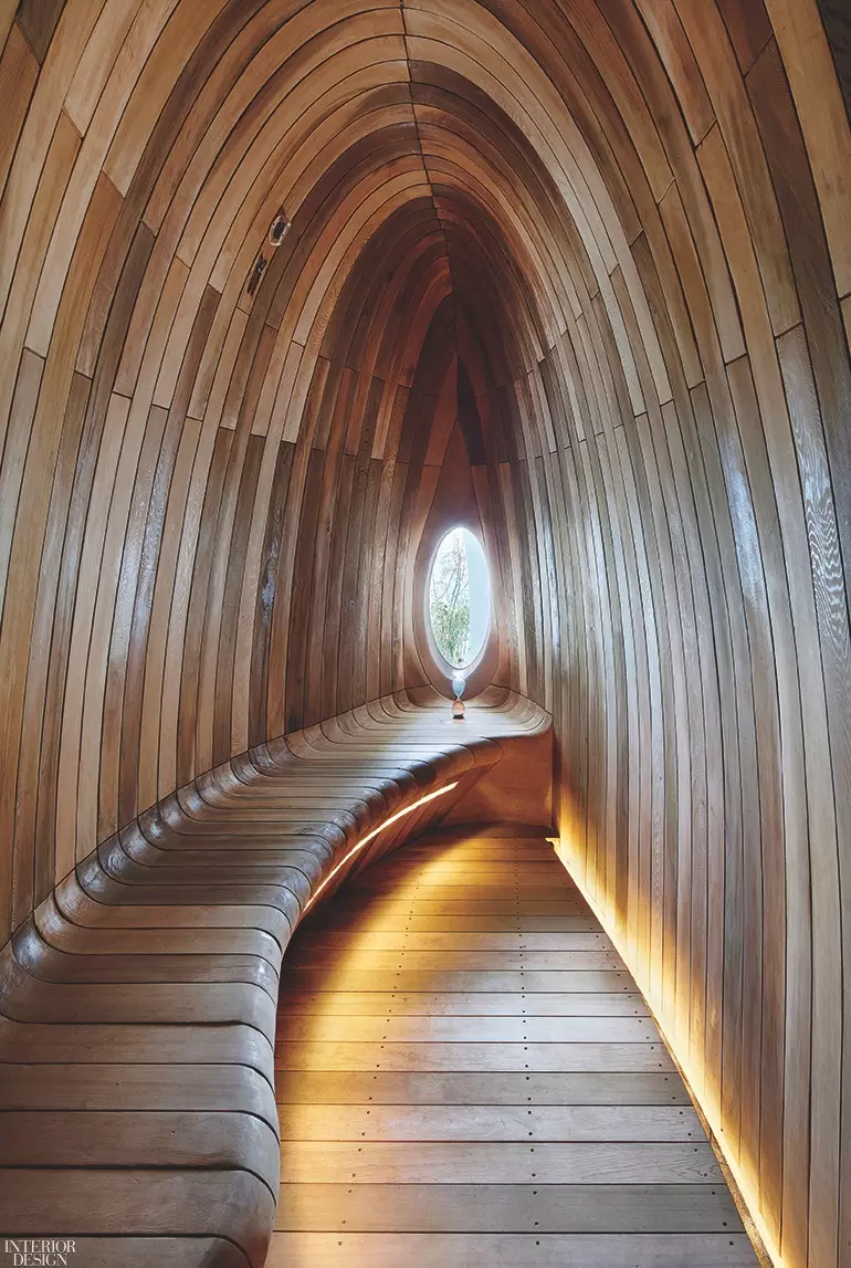 A wooden archway leads to a small oval window at one end, offering a curved bench for seating