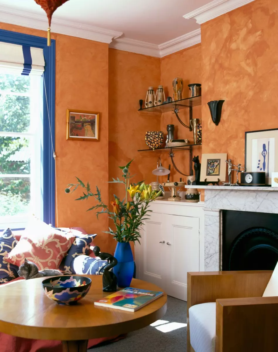 Gilt mirror above marble fireplace in nineties living room green wallpaper patterned curtains floral sofas