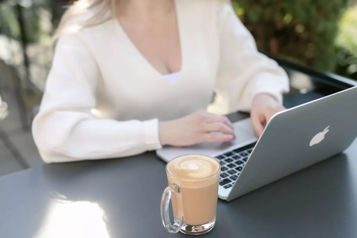 Woman working on laptop at outdoor patio.