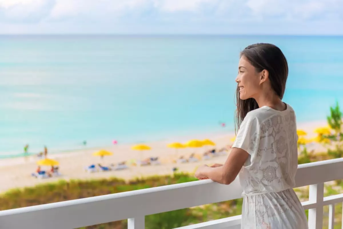 woman tourist enjoying ocean view from beach front hotel room on Caribbean holidays. - find a short-term apartment