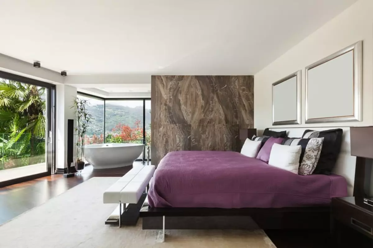 Bedroom with purple satin sheets, wood divider and corner bathtub