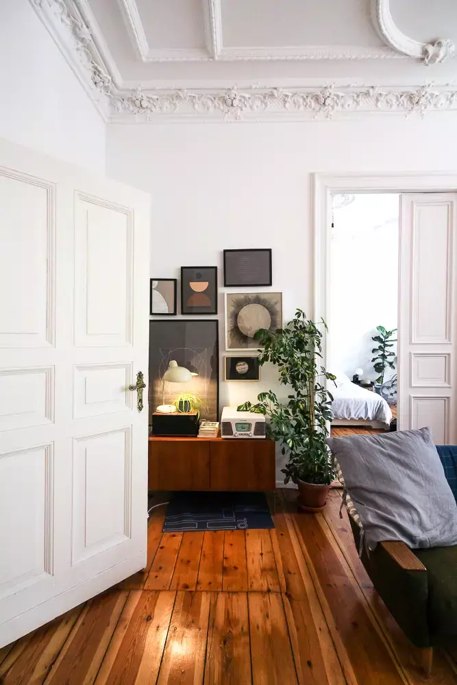 A room with detailed ornate molding, a couch, and a sideboard showcasing neoclassical interior design style