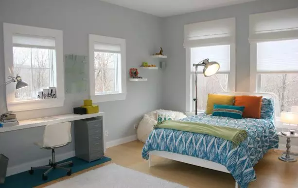 a cool blue and grey bedroom with warm-colored accent pillows