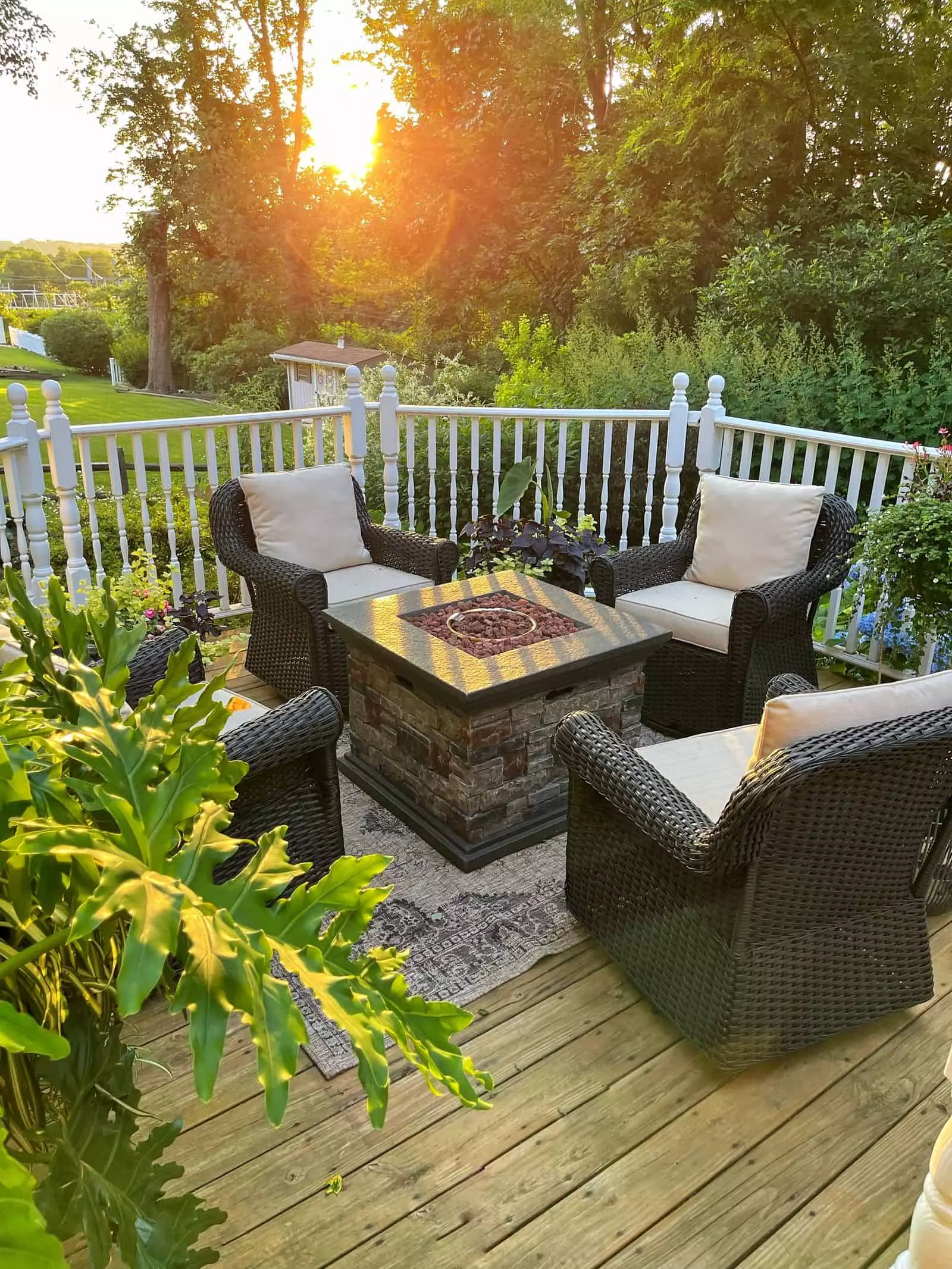 Close-up of outdoor dining space with a farmhouse table and outdoor wicker chairs - Gorgeous Backyard Ideas