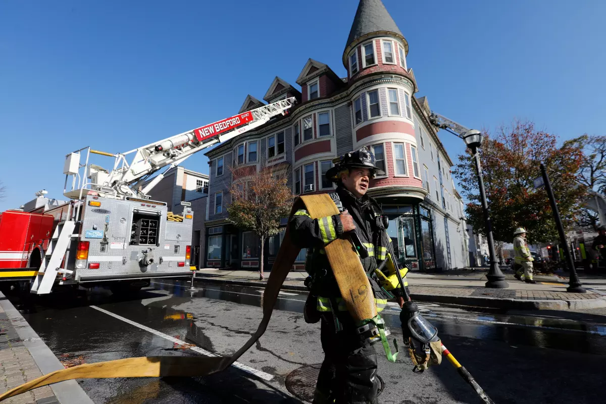 New Bedford firefighter Mark Pacheco carries the hose after responding to a fire at 1168 Acushnet Avenue in New Bedford. (Credit: PETER PEREIRA/The Standard-Times/FILE)