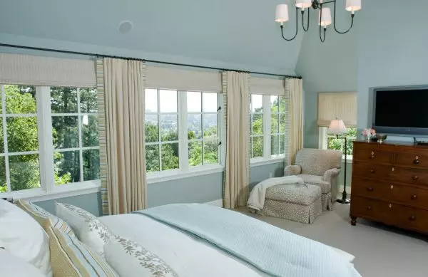 these roman shades with curtains make an enclosed living room feel lavish and bright