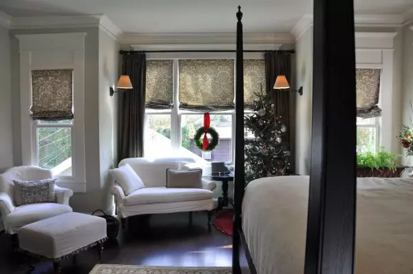 use roman shades with curtains to enhance the bay window view in the master bedroom