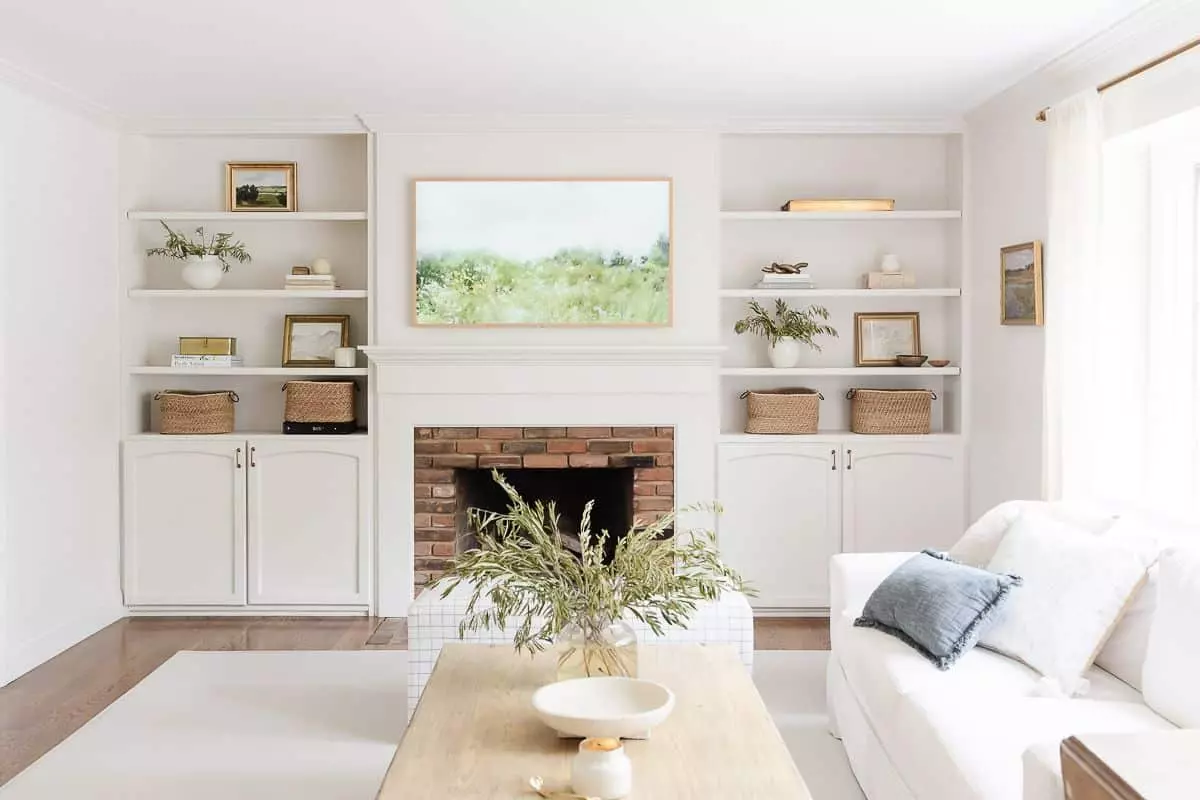 A white living room with bookshelf decor, a brick fireplace surrounded by built-ins.