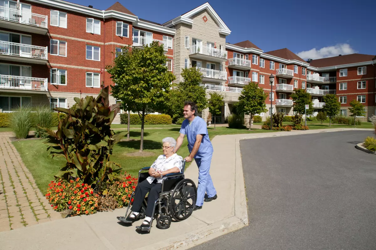 nurse or doctor pushing a wheelchair outdoors