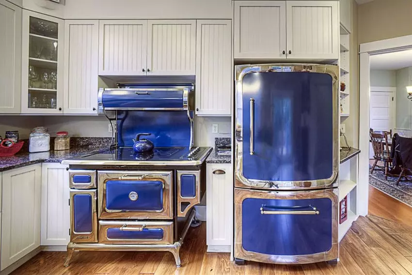 Kitchen with navy cabinets, plank flooring, and yellow pendants