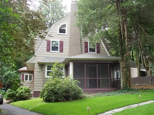 Beige Dutch Colonial house with red shutters