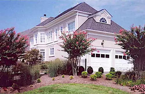 Stucco-sided Traditional home with multi-pane windows and eyebrow dormers