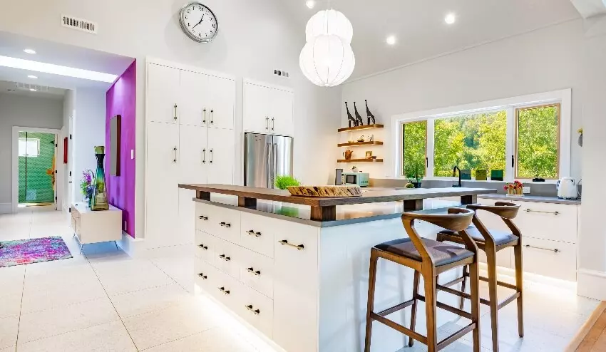 White and dark grey modern kitchen interior with under cabinet lighting, marble floor, and dining table