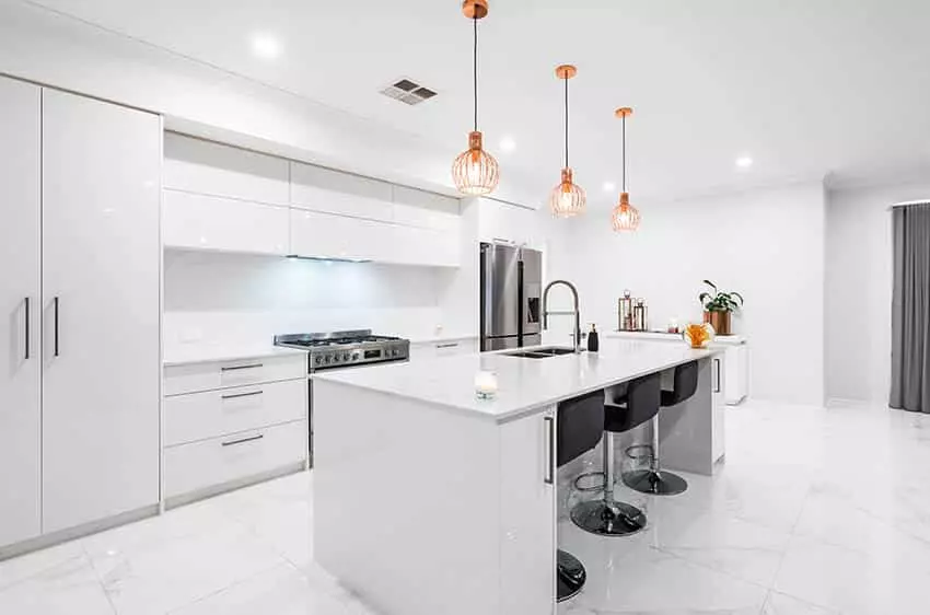 Kitchen with modern white high gloss cabinets silver hardware long calacatta countertop island wood flooring