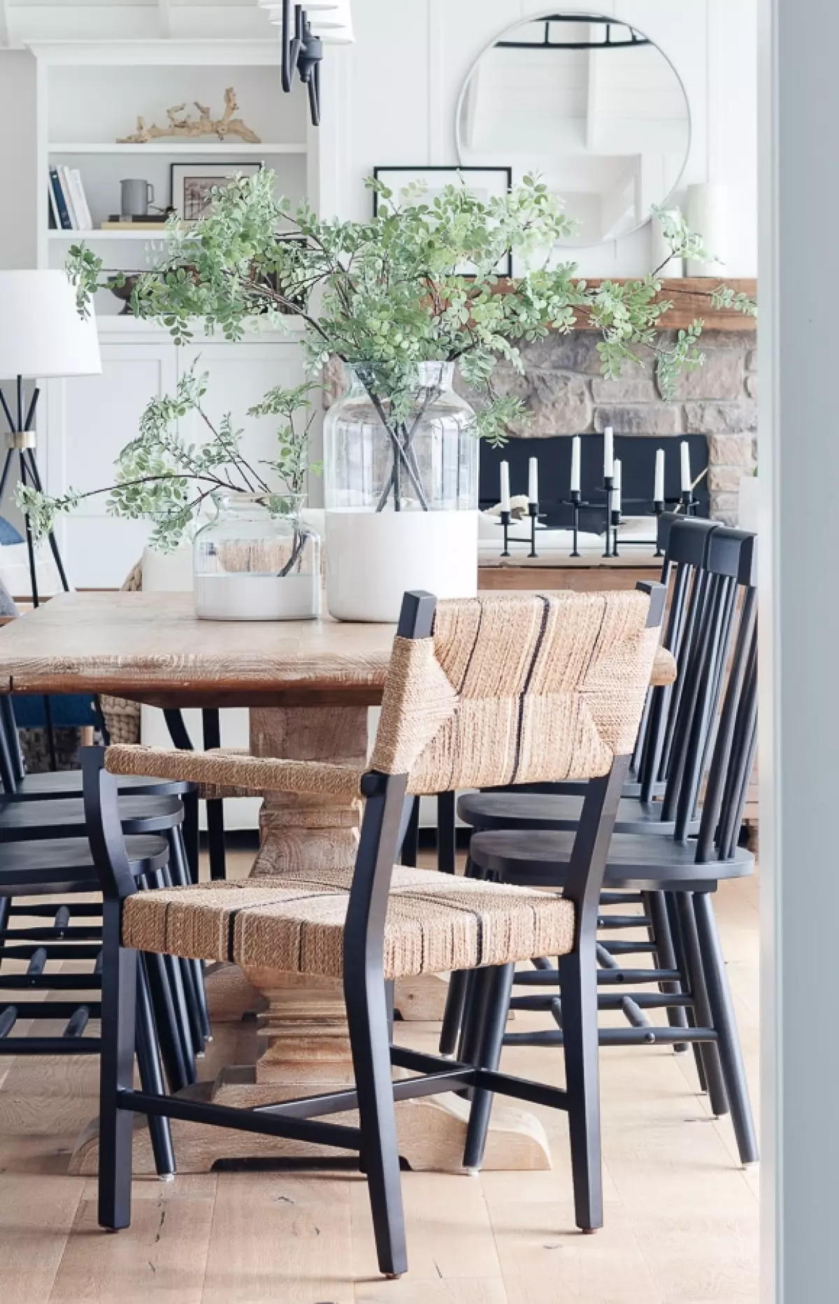 white lake house dining room with wood table and black and woven dining chairs