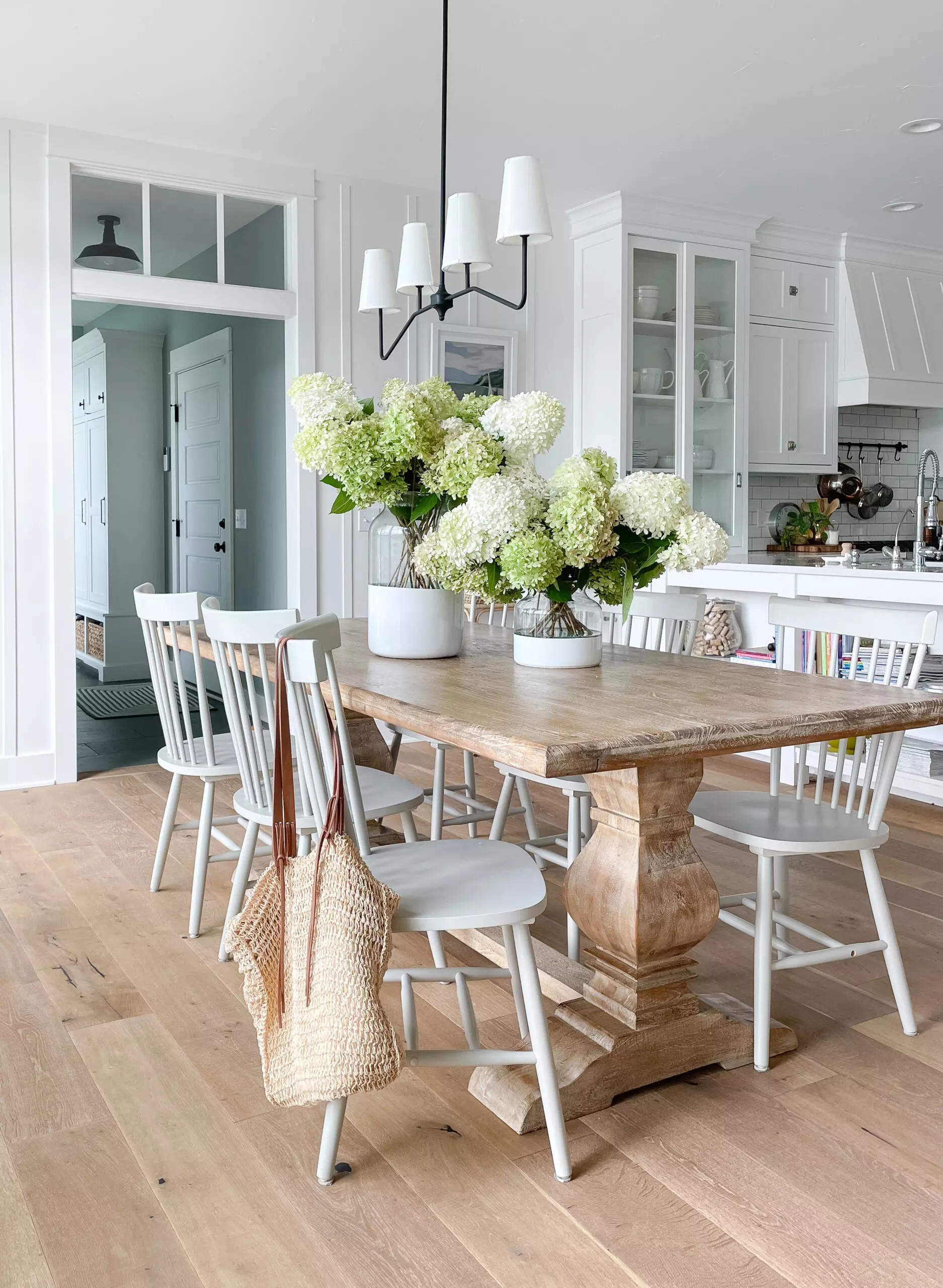 white lake house dining room with gray windsor chairs and hydrangeas centerpiece