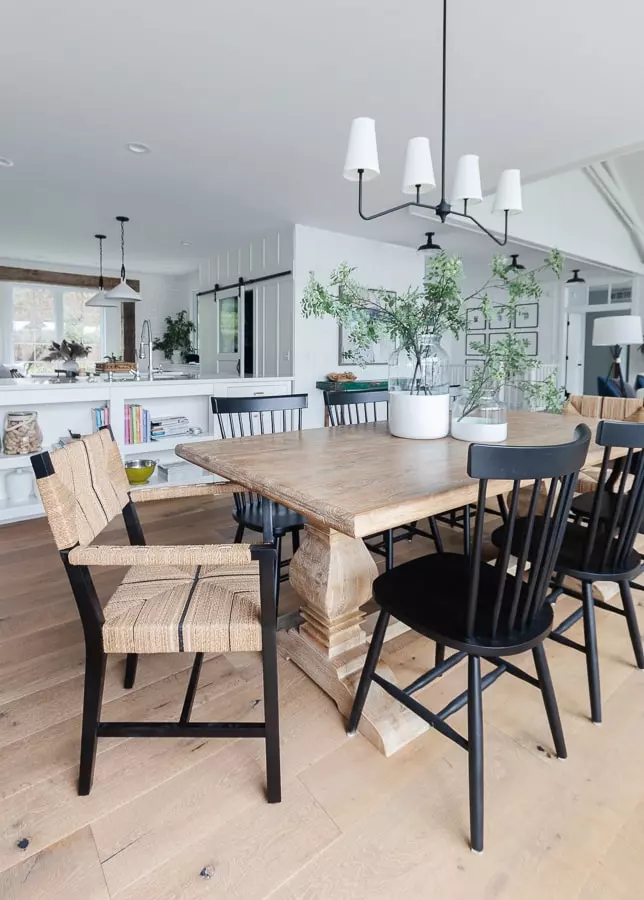 wood table with black chairs and white vases and adjacent living room