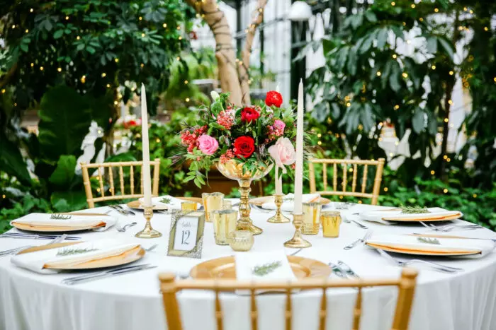 Design ideas for a restaurant table set up with green flowers and black chairs.