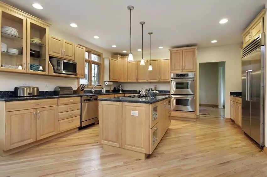 Modern kitchen with brown kitchen cabinets oversized kitchen island with bar stools granite countertops huge refrigerator and beige backsplash