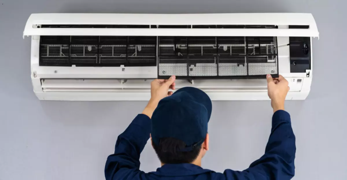 Technician service removing air filter of the air conditioner for cleaning and maintenance.