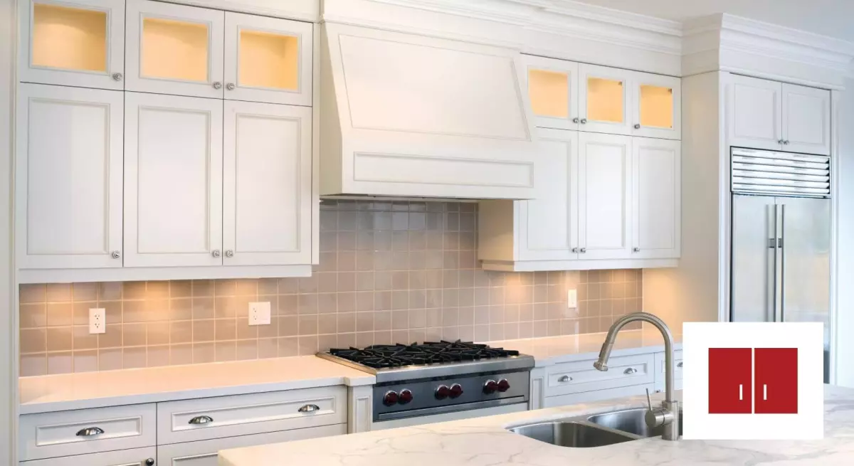 Simple white stock kitchen cabinets with brown tile backsplash.