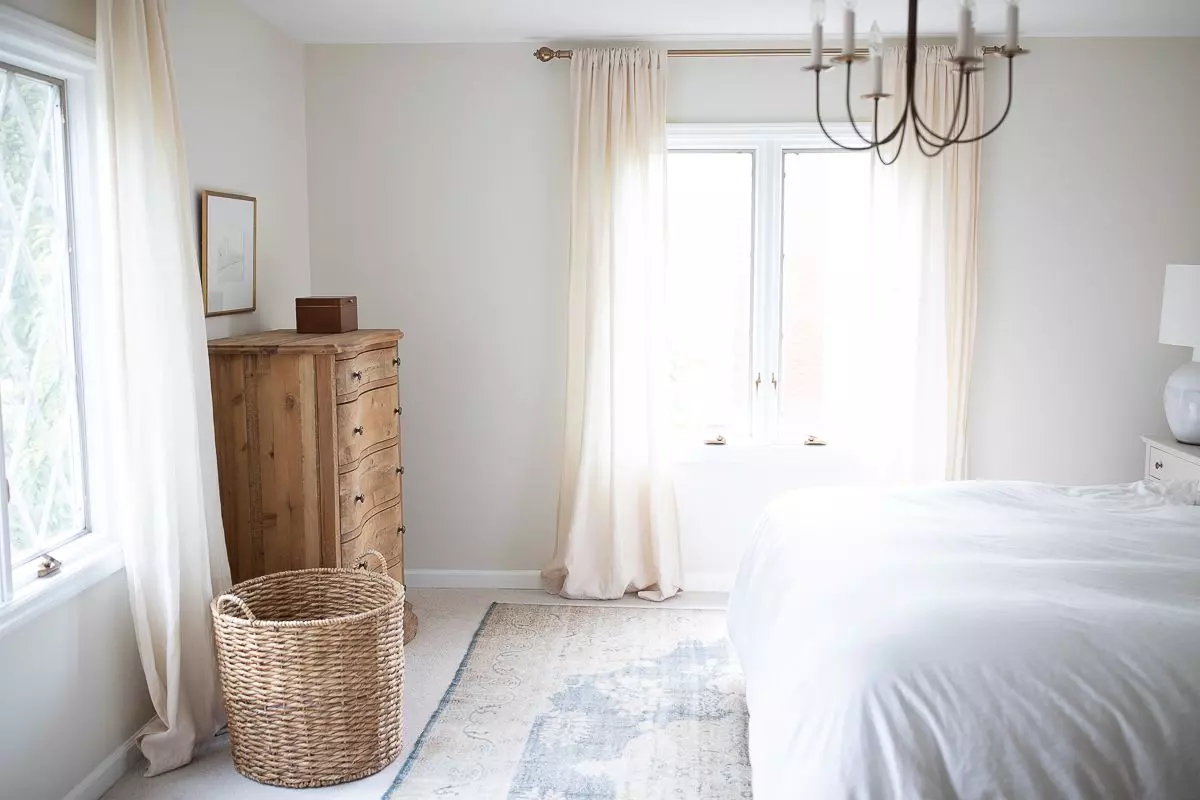 A primary bedroom with a vintage Turkish rug placed on top of carpeted floor and a wood dresser in the corner.