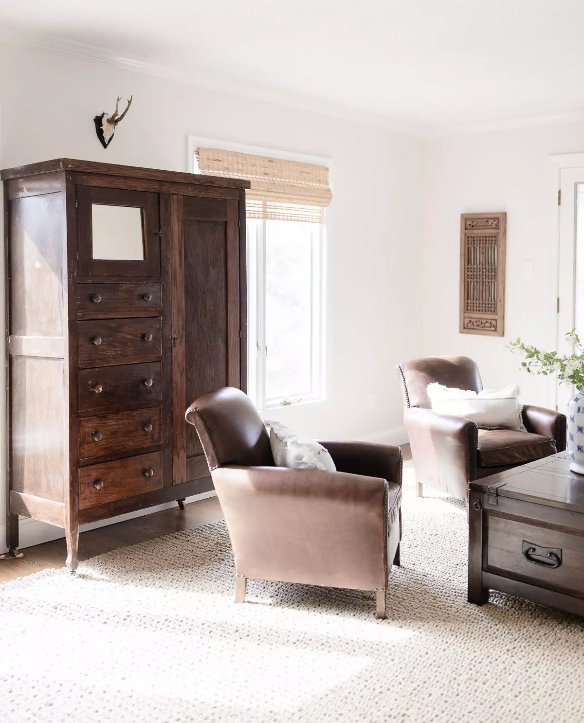 A living room in a cozy home featuring leather chairs and an antique wood armoire