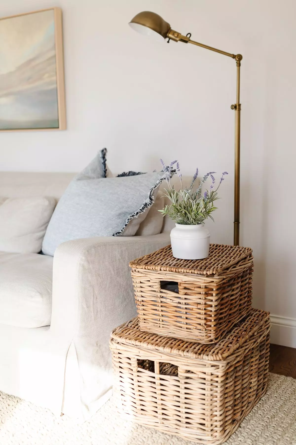 A linen sofa in a cream living room with textural baskets as a side table