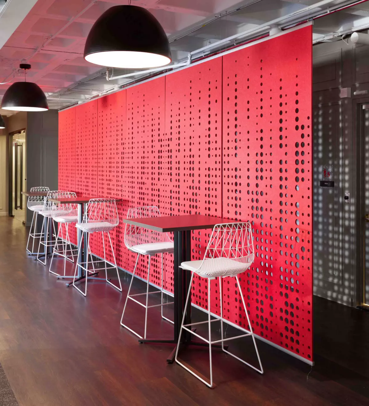 Two office spaces are separated using partitions. Two are white partitions, and the other has a wood appearance. There are black rolling chairs at each desk.