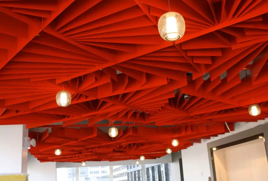 This image looks upward at a bright red patterned ceiling design with hanging light fixtures.