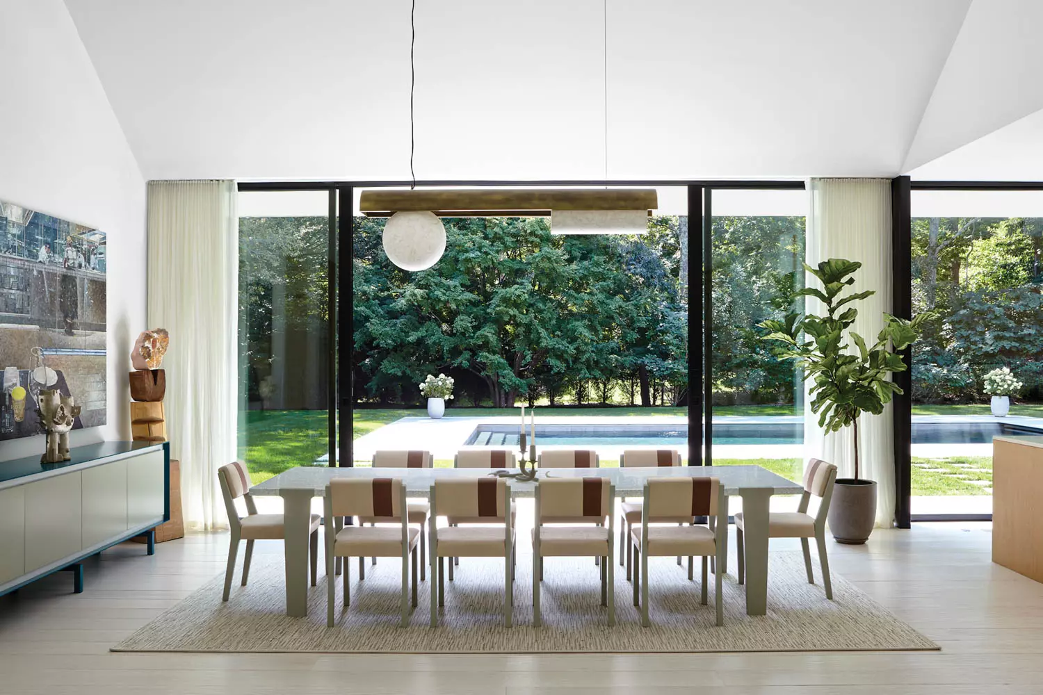 A dining room surrounded by glass walls looks over a pool at this home