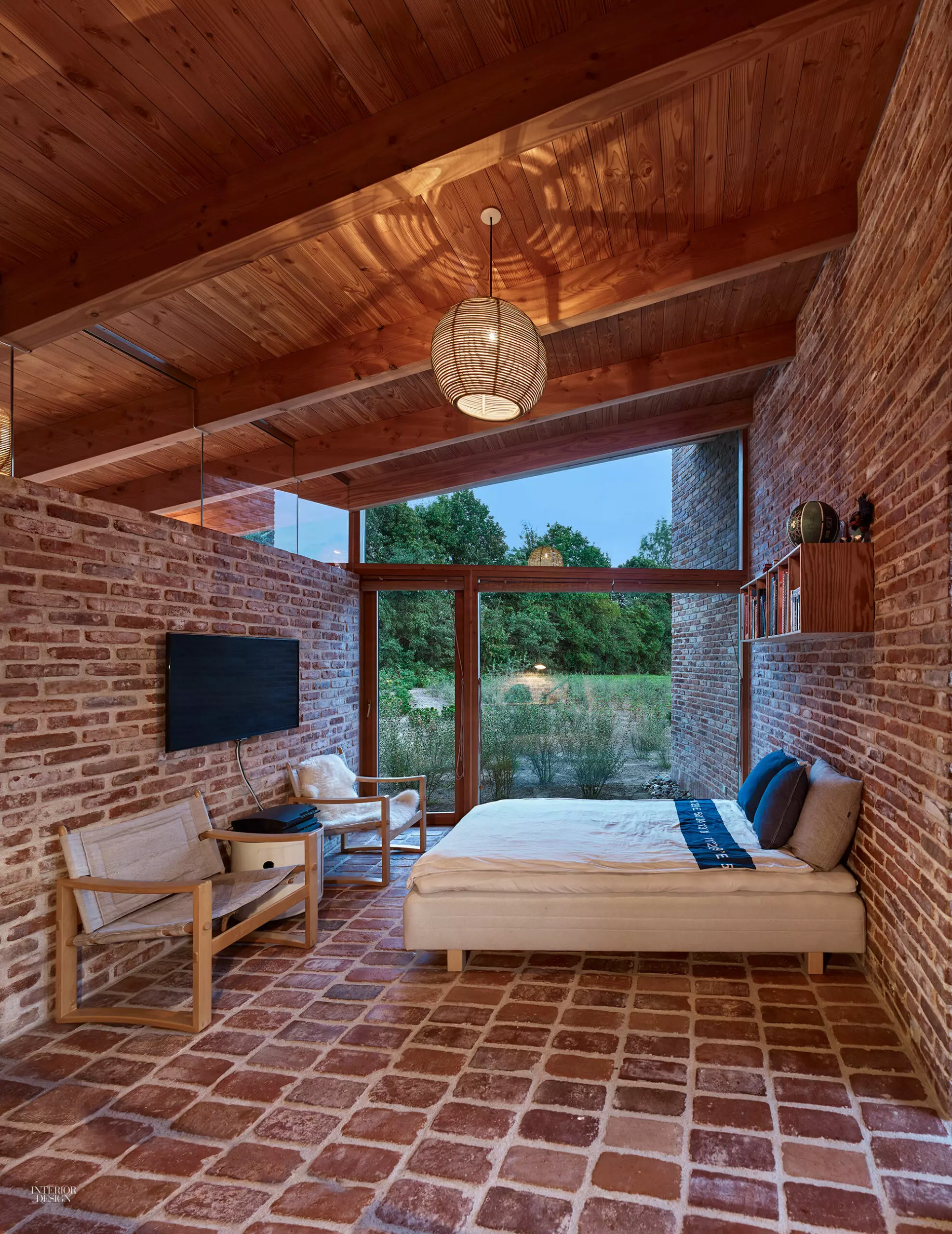 A cream bed in a brick room with tiled floors and wood ceilings