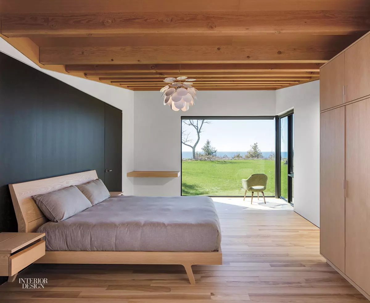 A gray bed against a deep blue wall with landscape views