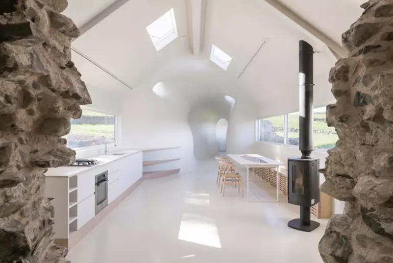 Stone walls frame this white kitchen area in a rustic country house