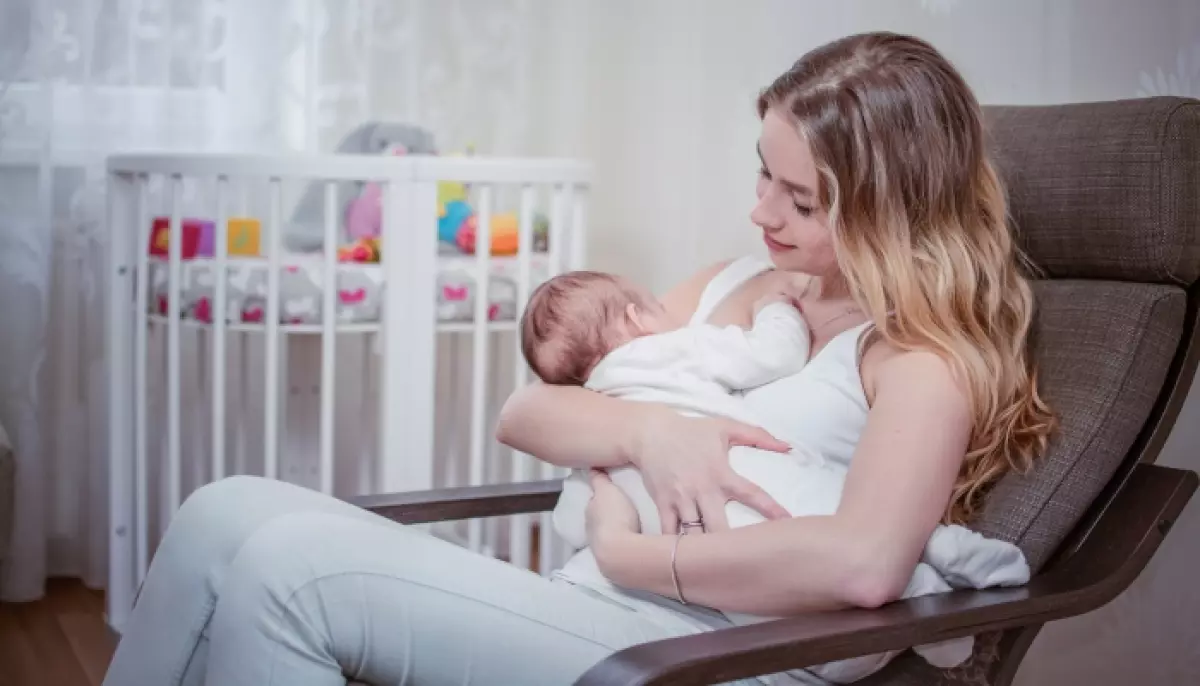 Breastfeeding baby near crib.