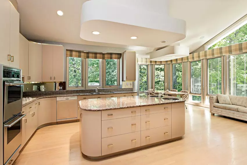 Kitchen with round island, red cabinets, sink, oven and backsplash