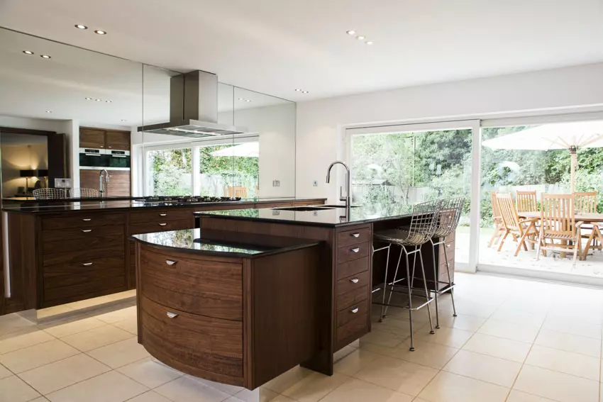 Kitchen with natural stone flooring, floating shelves and black chairs