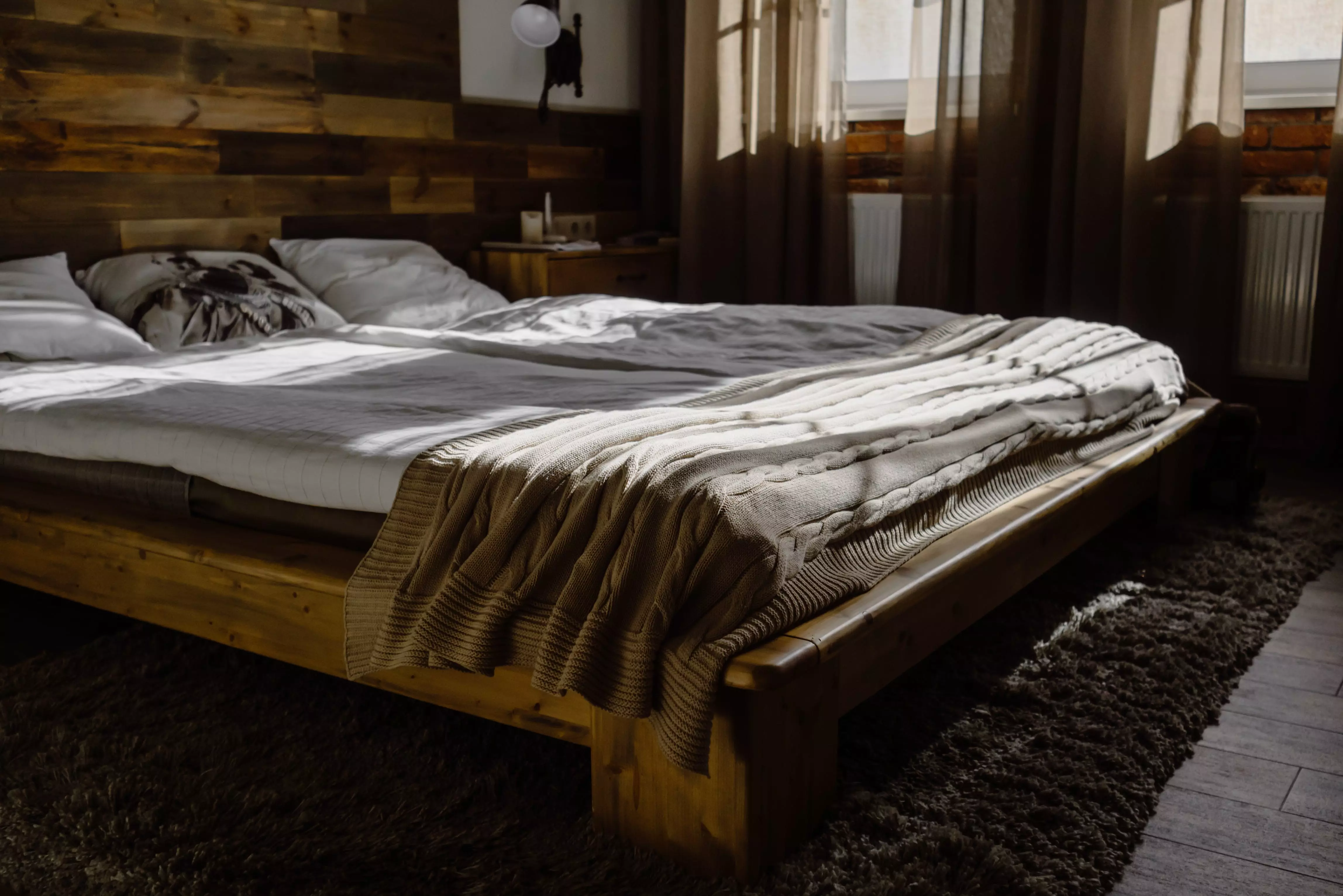 A Wooden Bed Frame with Mattress and Blanket